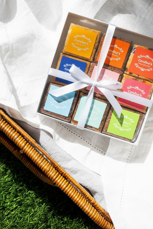 A gift box with an assortment of gourmet brownies displayed in front, some with descriptive tags indicating flavours.