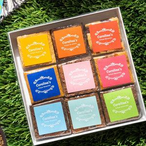 Box of colorful chocolates on grass with strawberries and a card