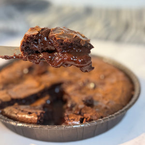 Chocolate brownie stuffed with chocolate ganache with a slice being lifted on a white plate