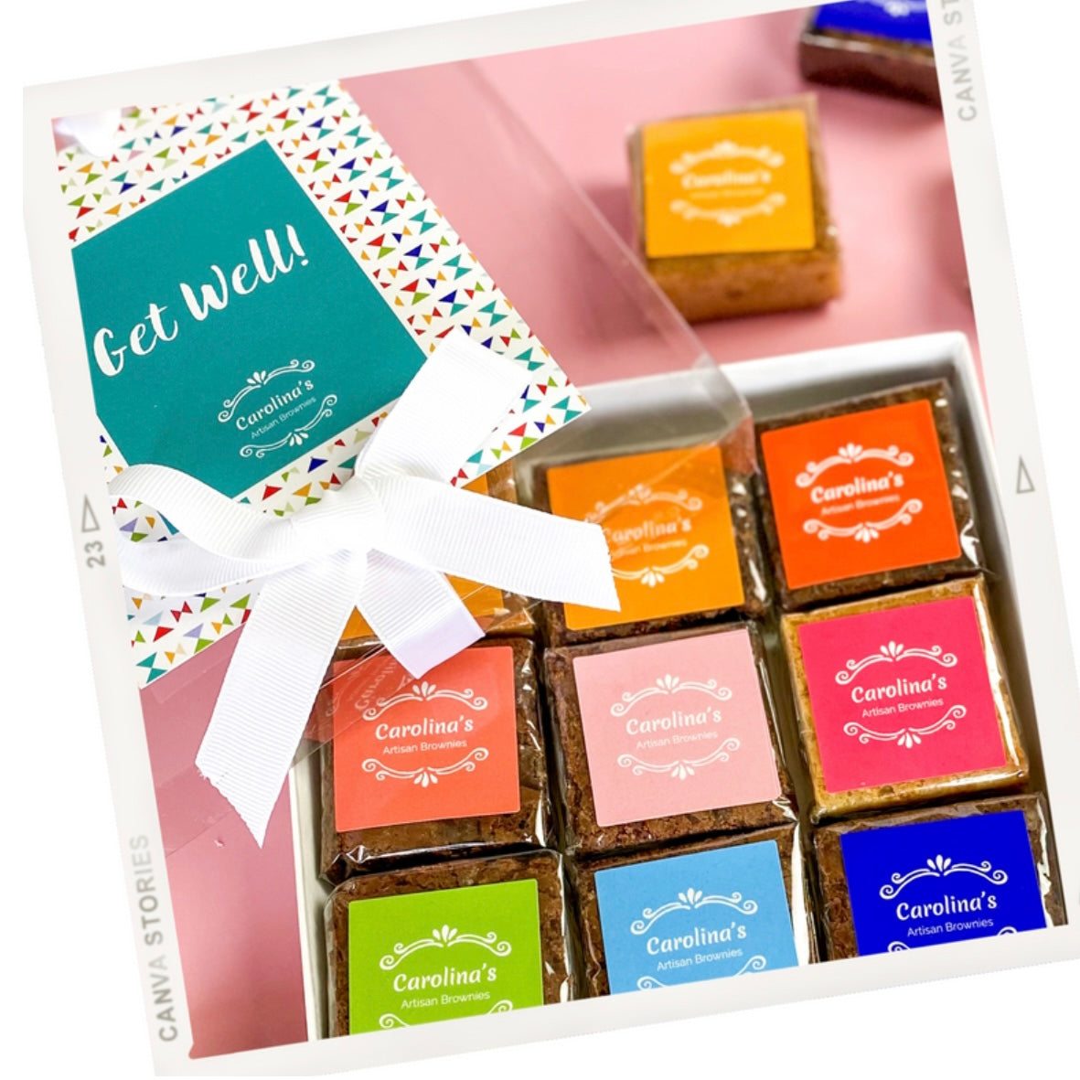 A gift box of assorted handmade brownies with colorful labels, one label reading 'Get Well'. The box is adorned with a white ribbon.