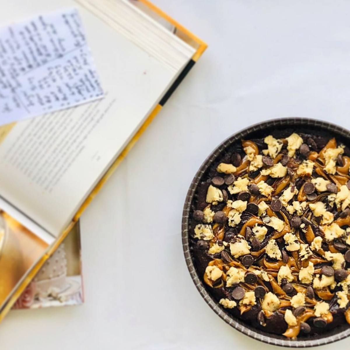 Carolina&#39;s brownie pie with cookie dough and chips on top and on the left a open recipe book