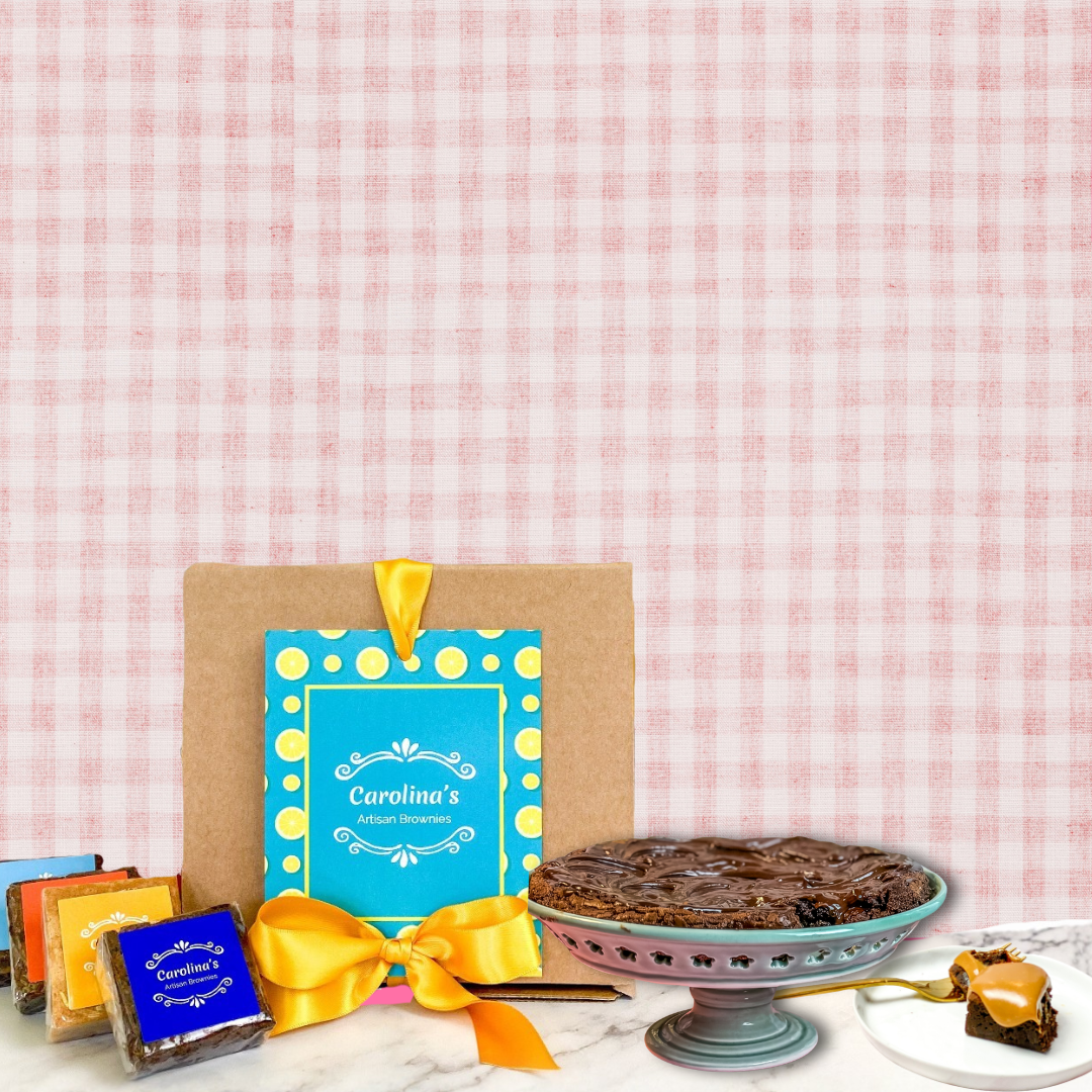 box of carolinas brownies with blue tag and yellow ribbon with a brownie torte on the side and scattered brownies on the other side